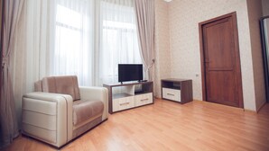 A modern living room with a sofa, TV stand, and wooden flooring.