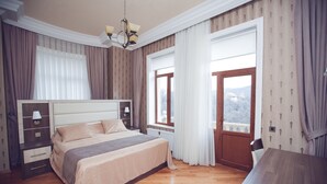 A bedroom with a large bed, a wooden dresser, a nightstand, and a window with curtains.