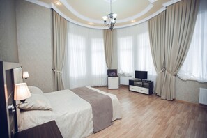 Un dormitorio con cama, mesita de noche, lámpara, televisión y cortinas.