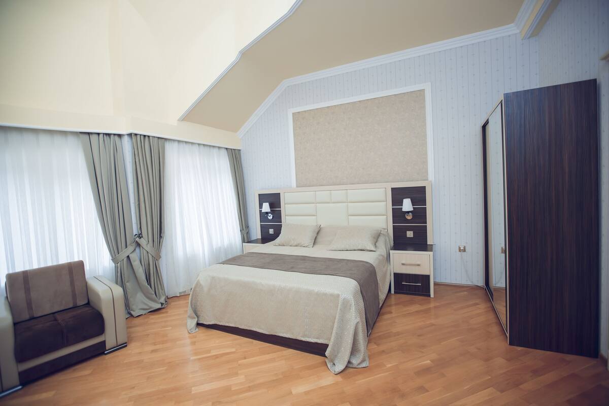 Een moderne slaapkamer met een groot bed, een nachtkastje, een stoel en een kledingkast.
