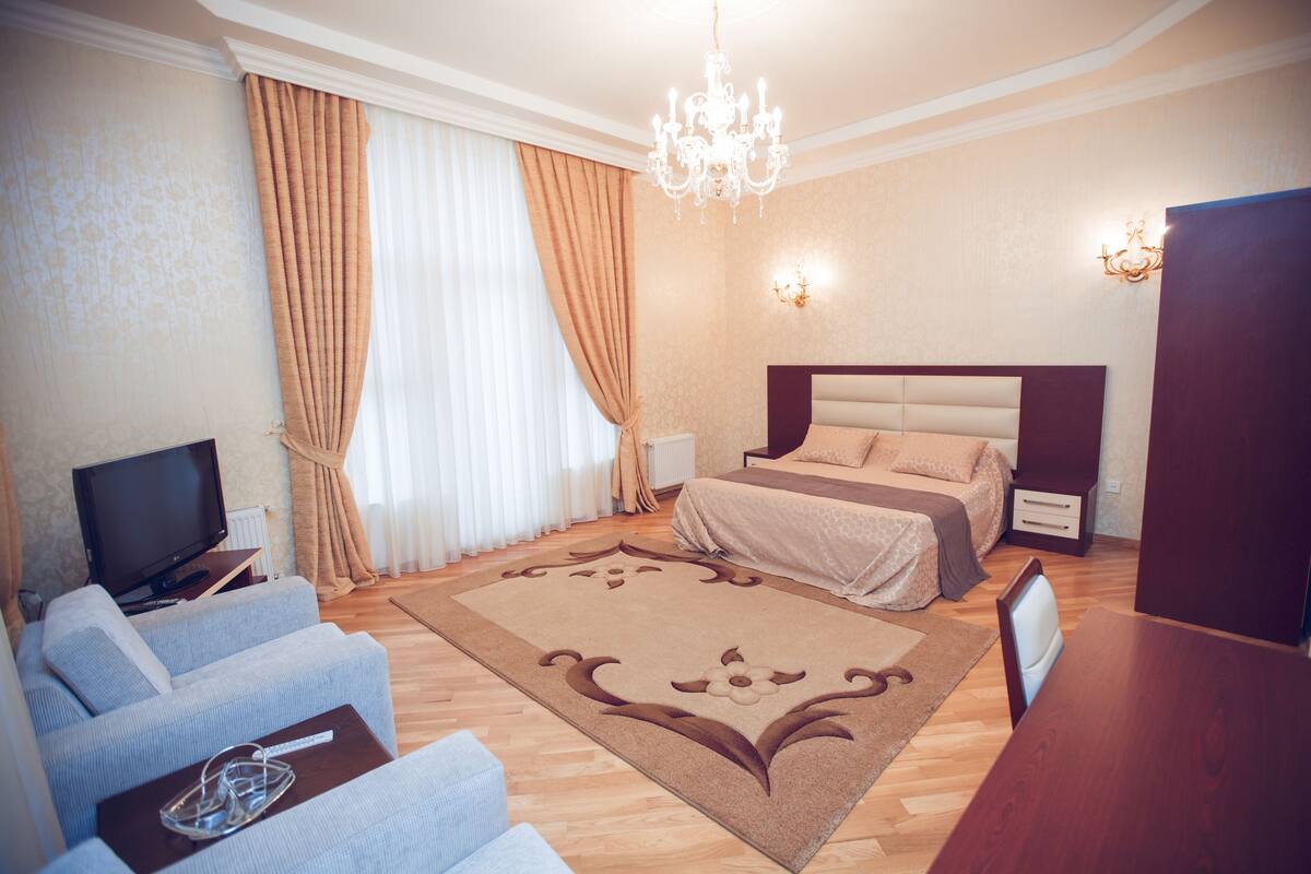 Een hotelkamer met een bed, een televisie, een bank en een kroonluchter.