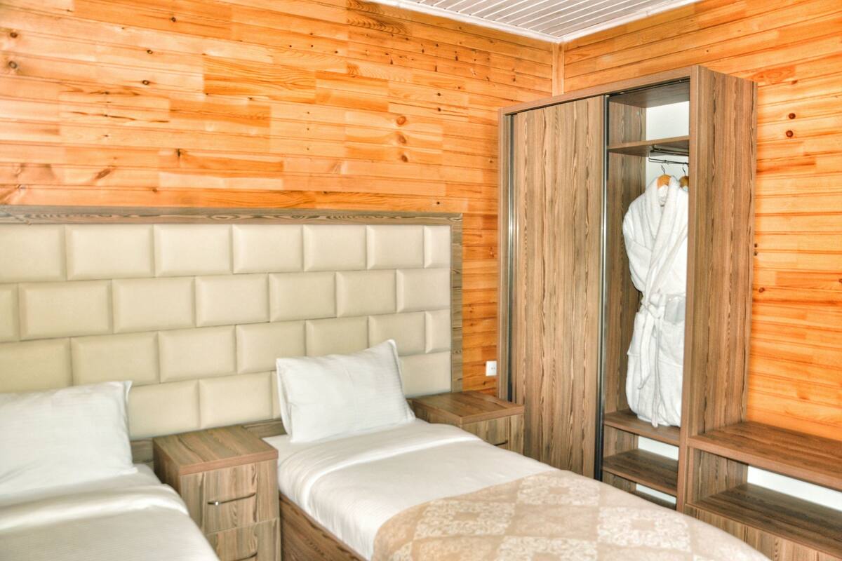 Een kamer met houten lambrisering, een bed, een nachtkastje en een kledingkast.