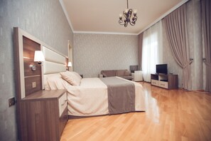 Un dormitorio moderno con una cama grande, mesitas de noche, un televisor y un candelabro.