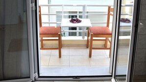 A room with a sliding glass door leading to a balcony with a white table and two chairs. - Chalkidonos (Heraklion)