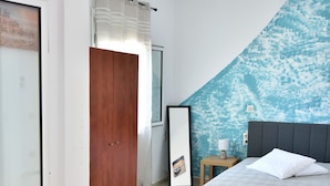 A bedroom with two beds, a wooden door, a mirror, a nightstand, and a table with a white cup. - Chalkidonos (Heraklion)