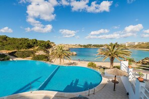 A swimming pool with a view of the sea, palm trees, and a beach. - Beautiful Apartment with Wi-Fi, Pool, Terrace and Sea View (Arenal d'en Castell)