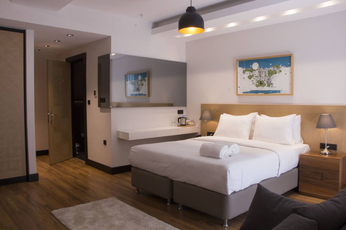 Un dormitorio moderno con una cama grande, mesitas de noche, un espejo y un cuadro en la pared.