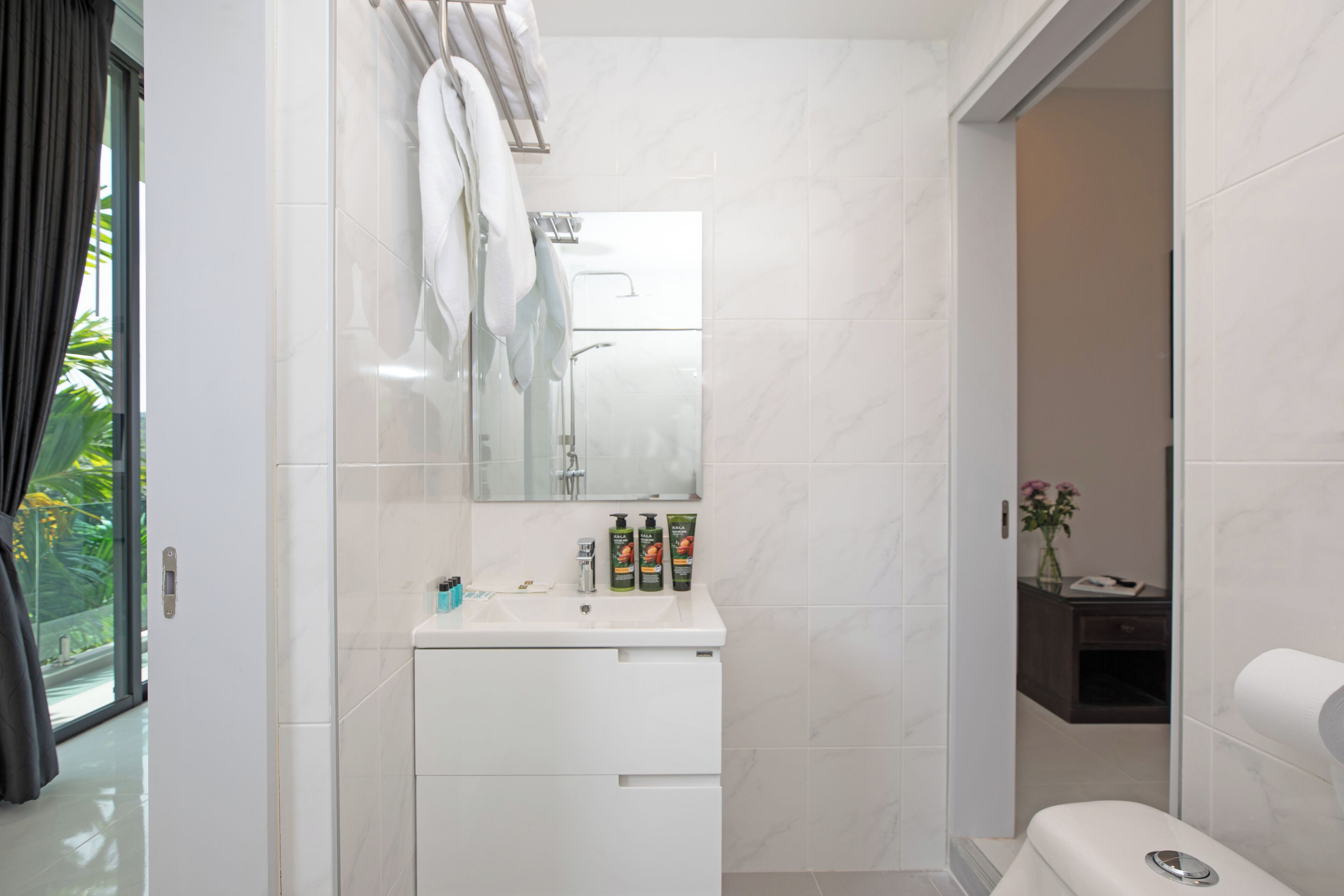 A modern bathroom with a white sink, mirror, and toilet.