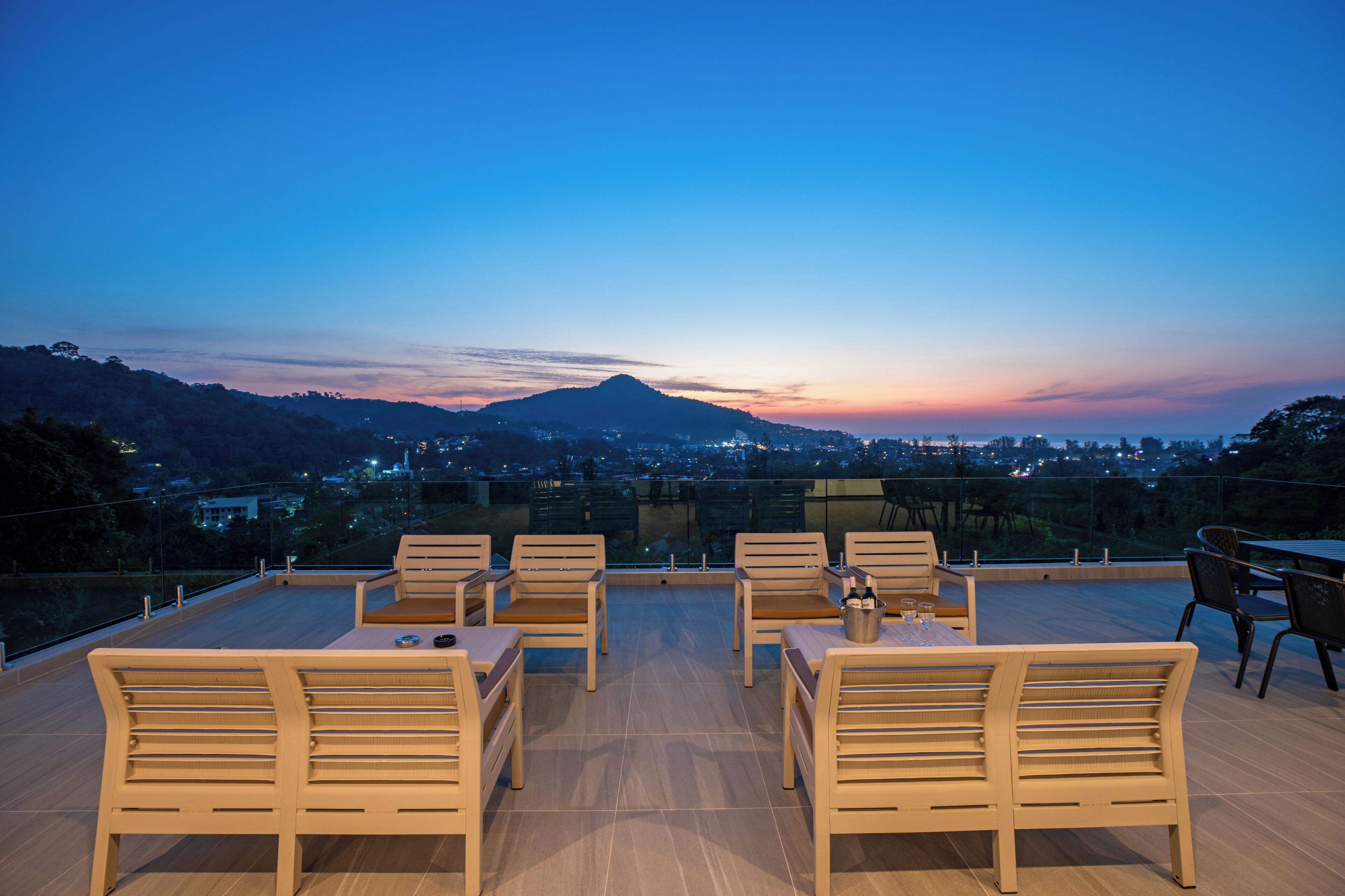 Eine Dachterrasse mit Holzmöbeln und Blick auf die Stadt im Abendlicht.
