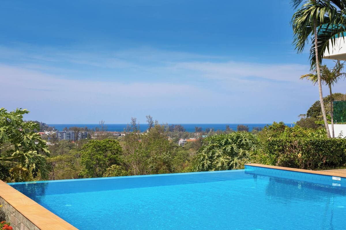 A clear blue pool with a view of the ocean and buildings in the distance.