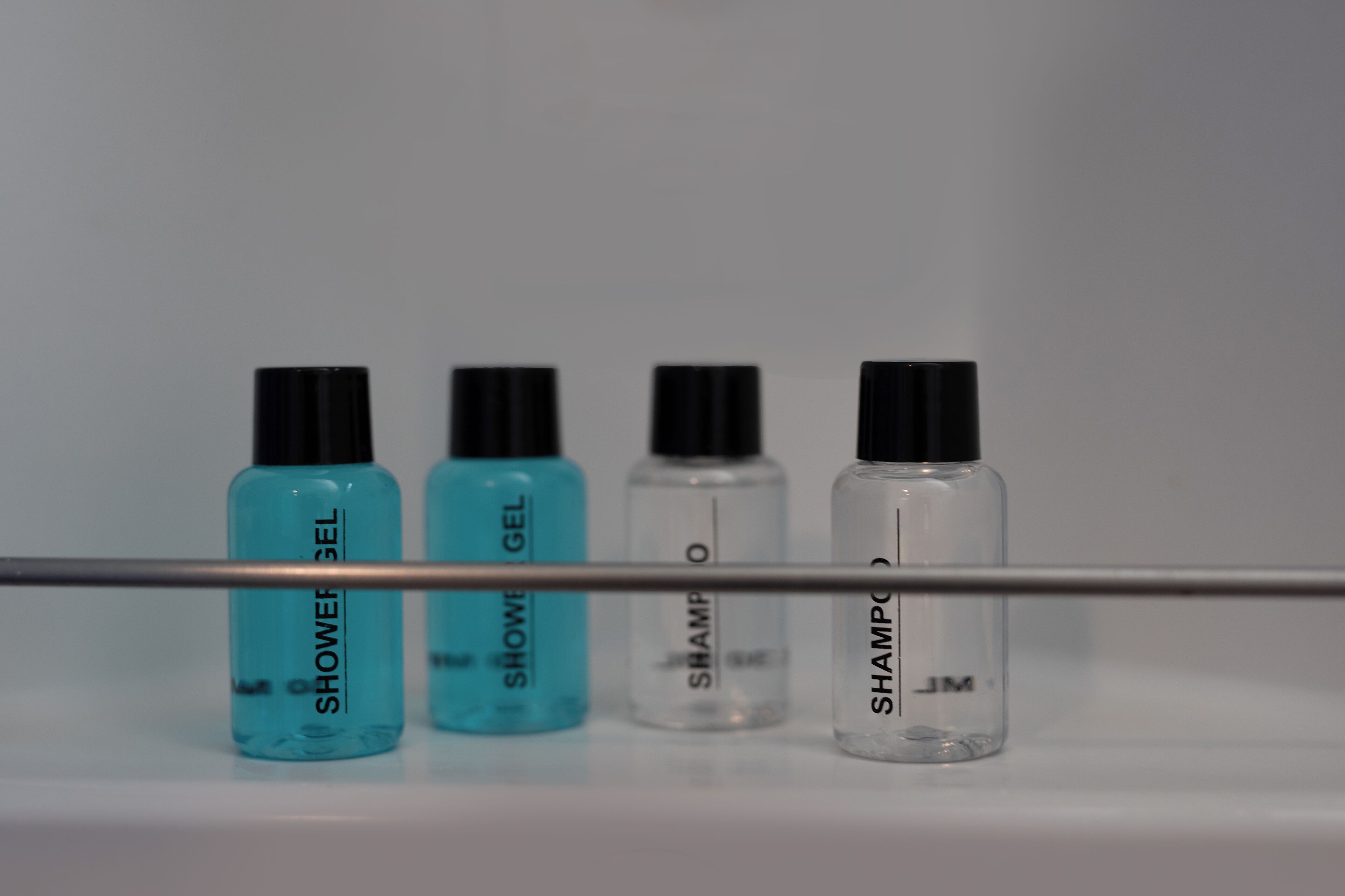 Four bottles of shower gel and shampoo on a white surface.