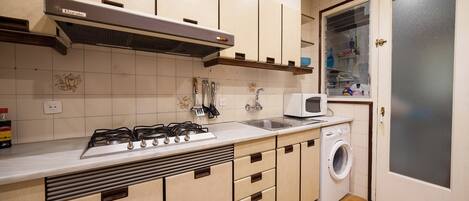 Cocina compacta con estufa a gas, microondas y lavadora integrada.