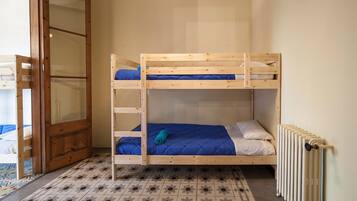 A bunk bed room with a wooden door, a radiator, and patterned flooring.