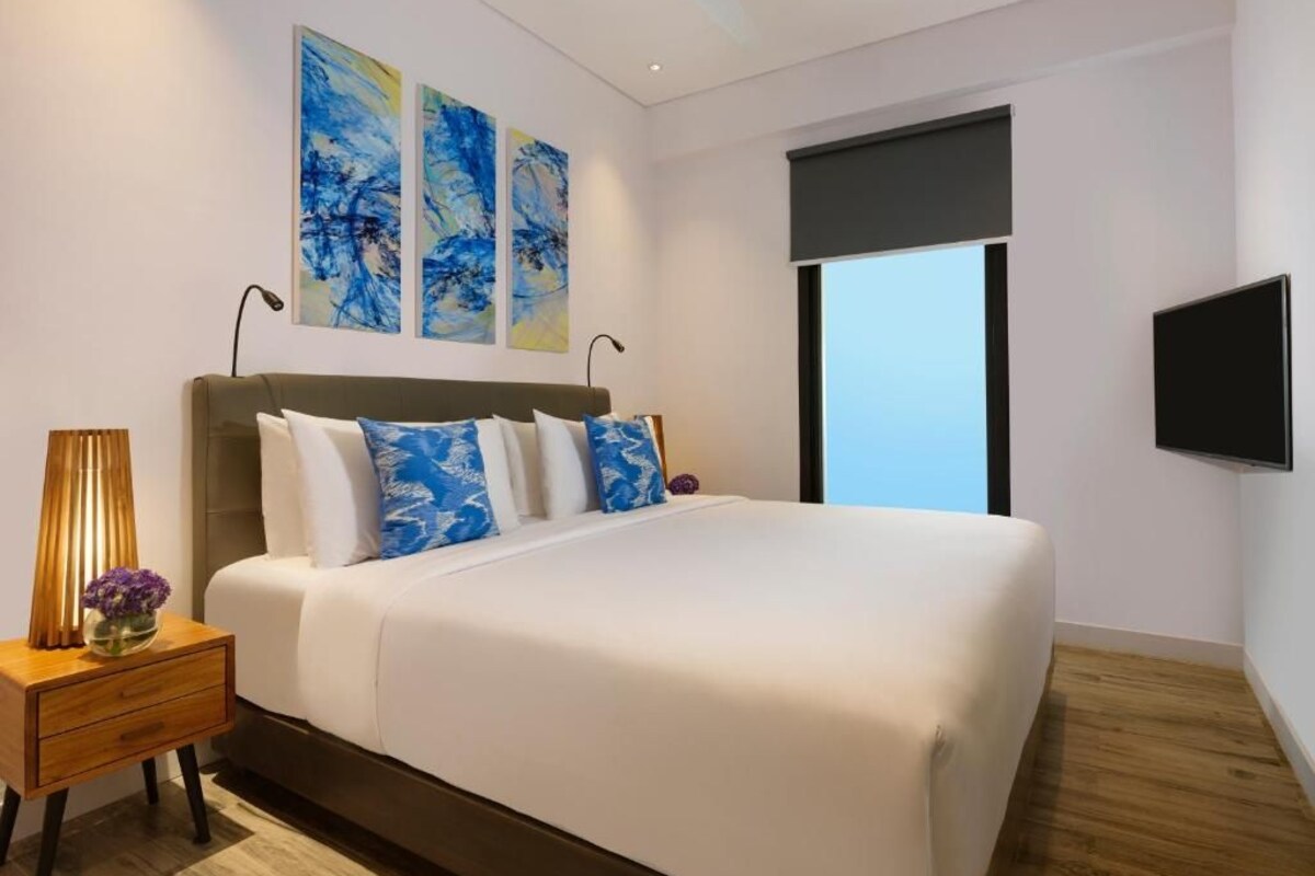 Una habitación de hotel moderna con una cama grande, un televisor de pantalla plana y arte abstracto en la pared.