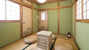 A traditional Japanese room with tatami flooring, shoji screens, and a tatami mat storage chest. - Sano san chi (Izumisano)
