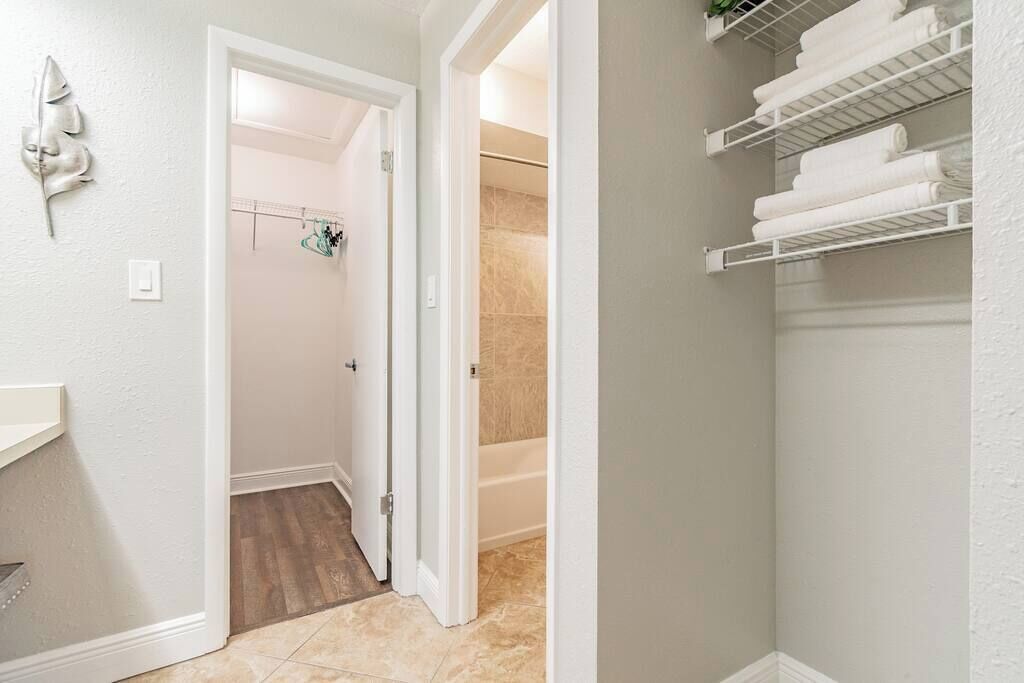 Une salle de bain équipée d’une douche, d’un porte-serviettes et d’une étagère où sont pliées les serviettes.