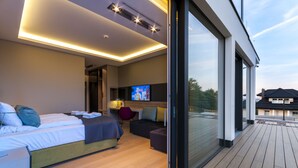 A modern hotel room with a large bed, a desk, a TV, and a balcony with wooden flooring. - Przystan Mechelinki - Marina del Mar (Kosakowo)