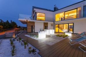 Una casa moderna con terraza, mobiliario exterior y ventanas amplias.