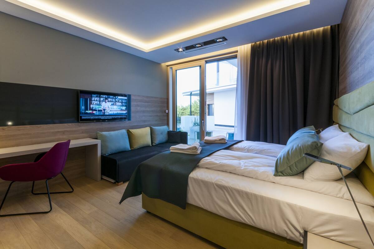 Une chambre d’hôtel moderne équipée d’un lit, d’un bureau, d’une chaise et d’un téléviseur.