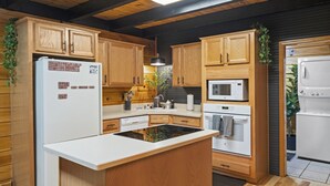 A modern kitchen with wooden cabinets, a central island, a refrigerator, a microwave, and an oven.
