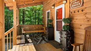 A wooden cabin with a porch, a bench, potted plants, and a sign reading 'Kilsides Haven'.