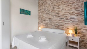 Quarto com cama, duas mesas de cabeceira, uma obra de arte na parede e parede texturizada.