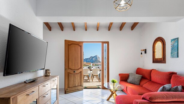 Uma sala de estar moderna com uma televisão de tela plana grande, um armário de madeira, um sofá vermelho e uma mesa de centro de vidro.