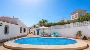 Uma piscina com espreguiçadeiras e plantas em vasos.