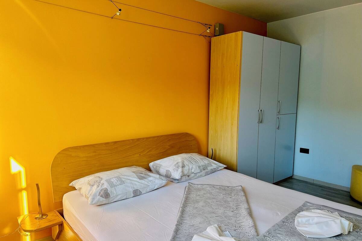 Une chambre d’hôtel comprenant un lit, une table de chevet, une armoire et une petite table de nuit avec une lampe.
