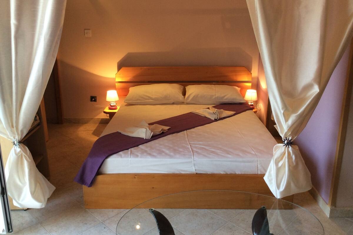 Une chambre d’hôtel avec un lit, deux lampes de chevet et des rideaux.