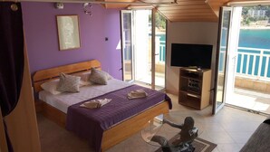 Une chambre avec un lit, une télévision et une vue sur la mer.