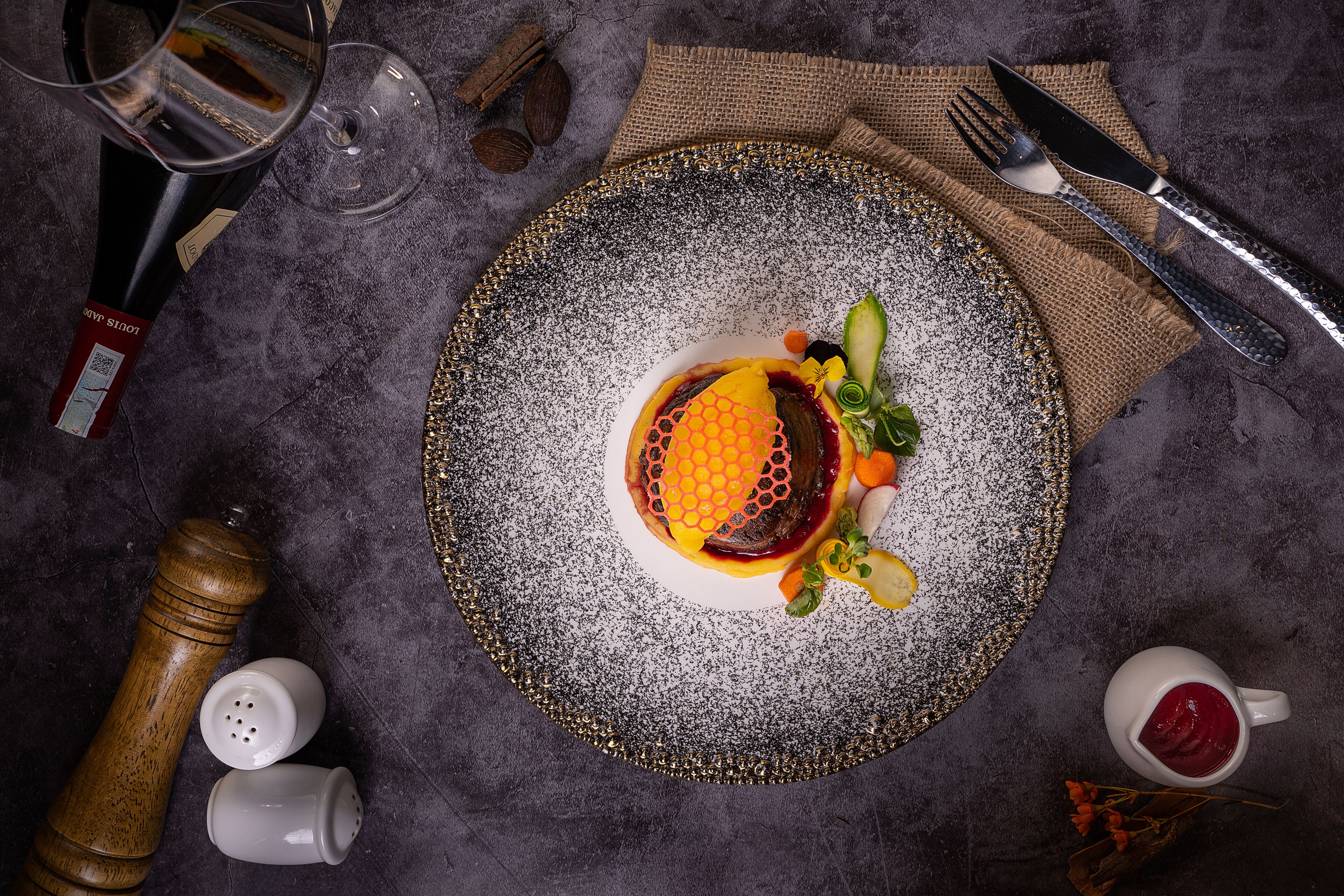A dining table with a plate of food, a wine bottle, a glass, and cutlery.