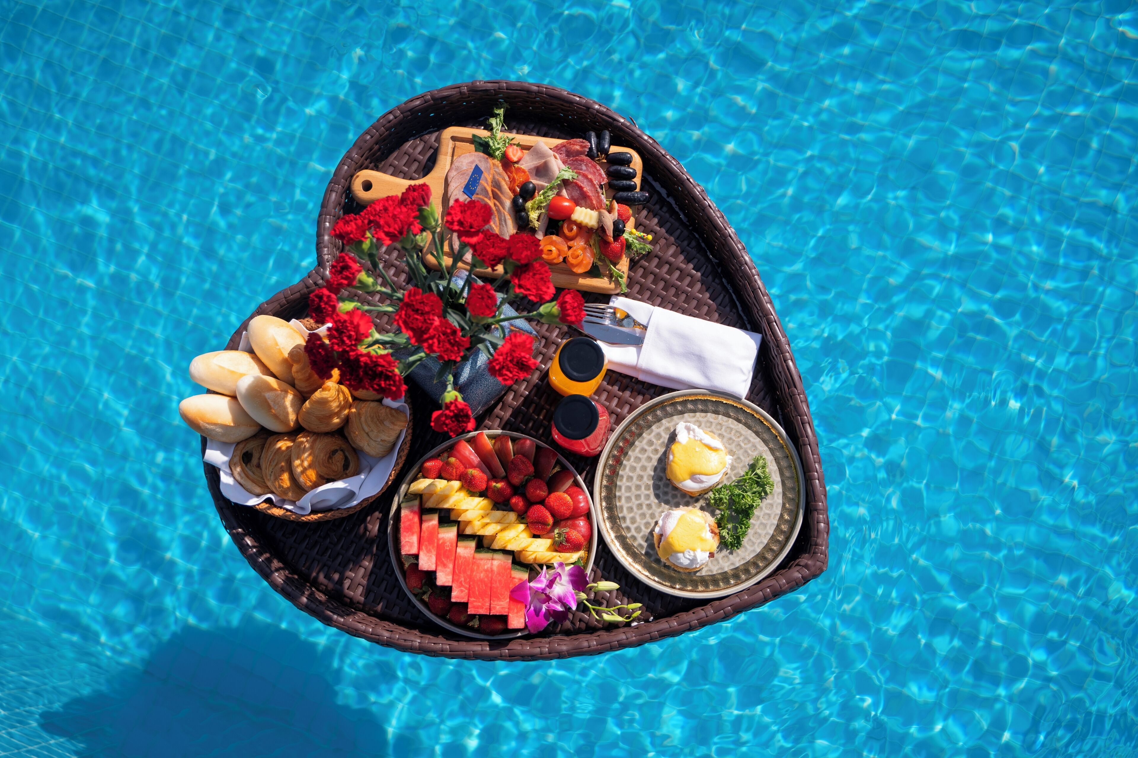 A tray with various foods and drinks by a pool.