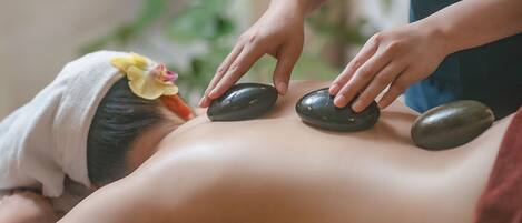 A person receiving a stone massage on their back.