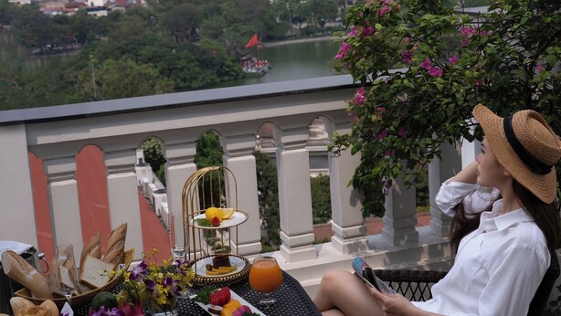 Un balcón con una mesa dispuesta para el desayuno, con vistas a un paisaje urbano.