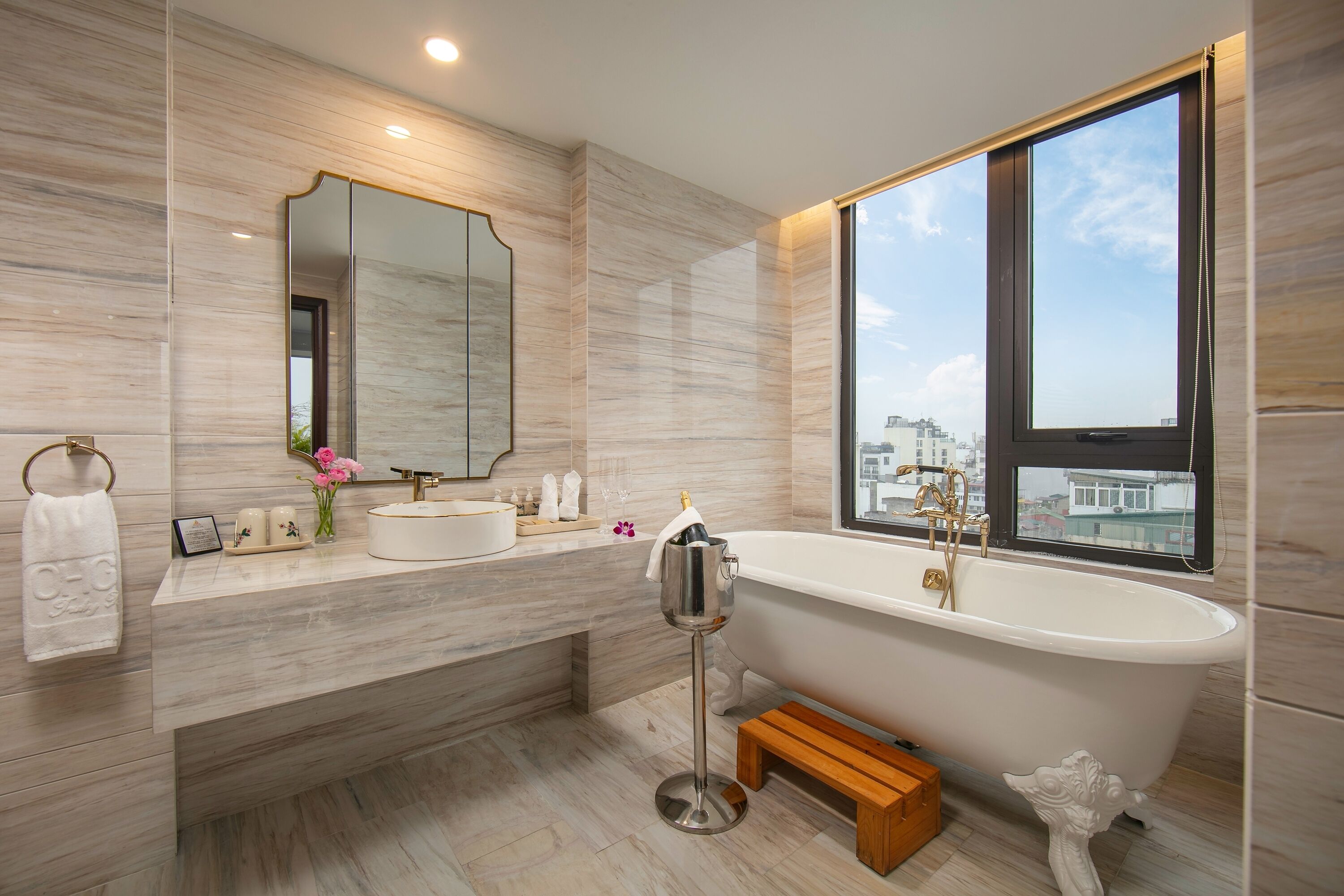 A modern bathroom with a freestanding bathtub, a large mirror, and a view of the city through a window.