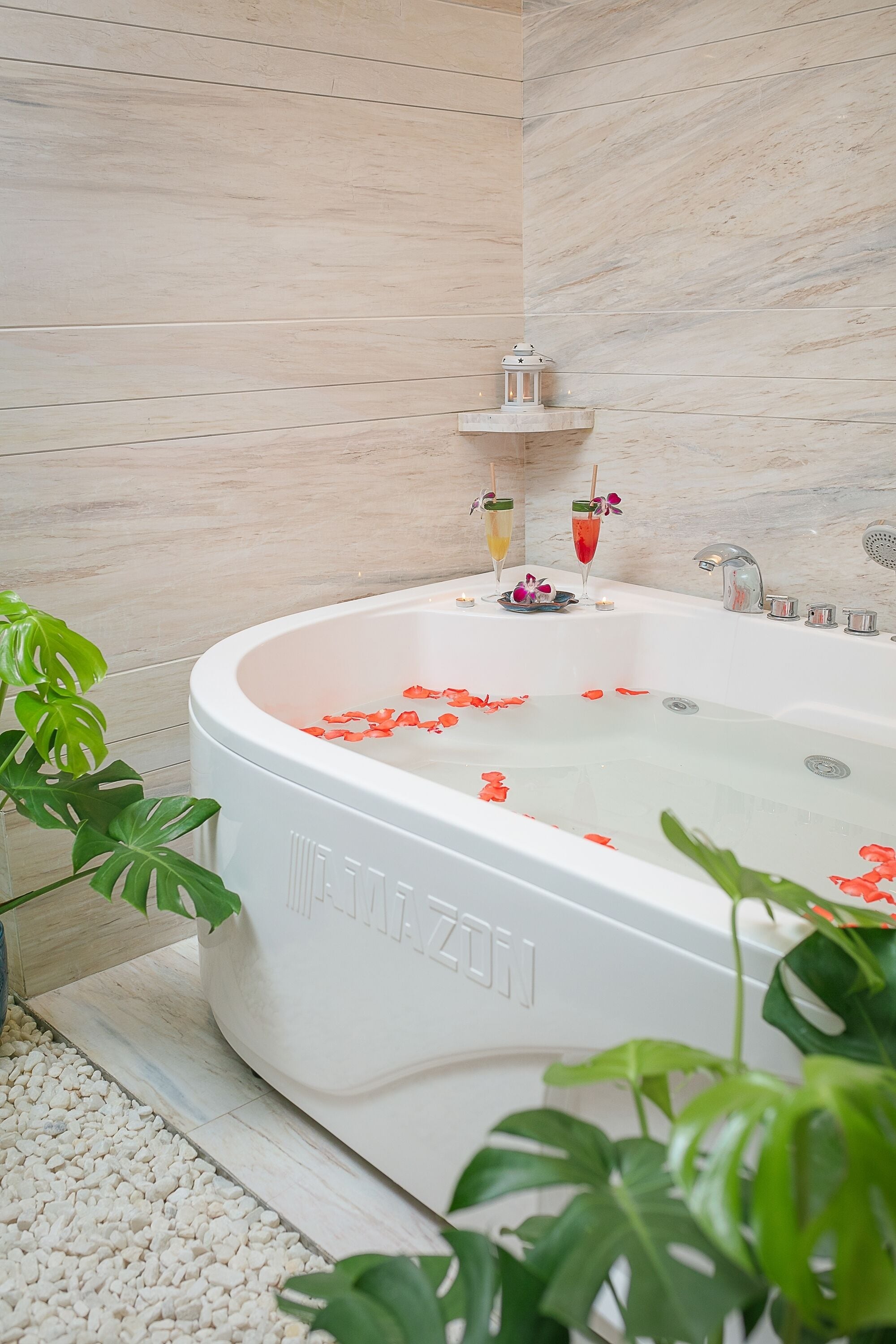 A modern bathroom with a freestanding bathtub, a small shelf with a lantern, and decorative flowers.