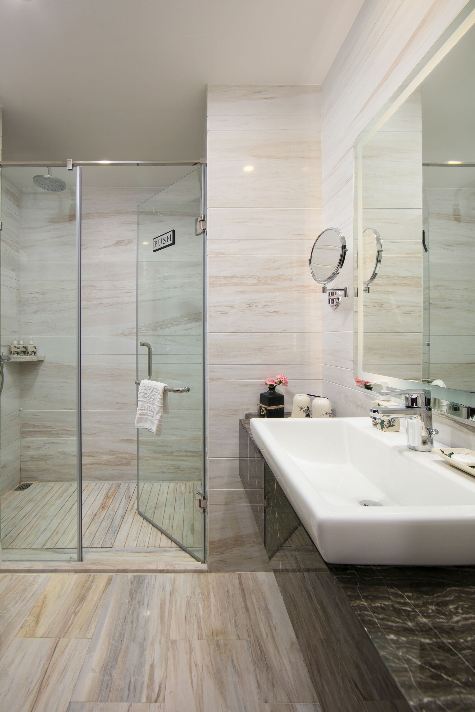 A modern bathroom with a glass shower enclosure, a large mirror, and a white sink.