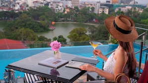 Una persona sentada a una mesa con vistas a un paisaje urbano y una masa de agua.