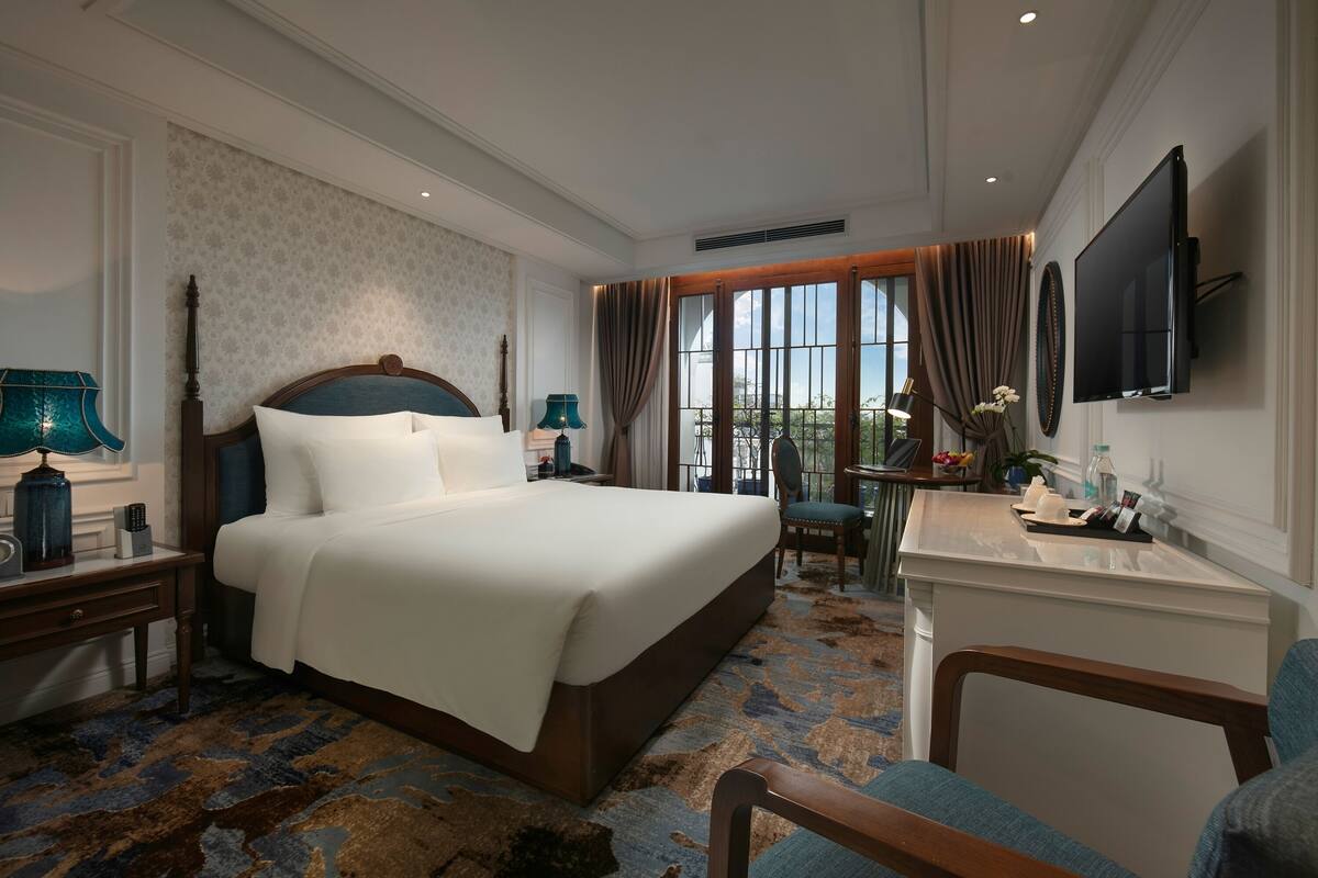 Habitación de hotel con una cama grande, un escritorio, un televisor y vistas al exterior.