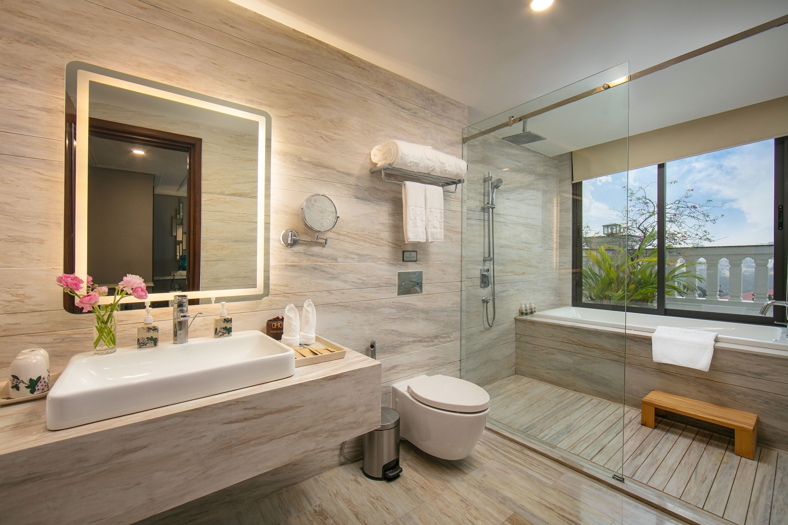 Un baño moderno con un espejo grande, un lavamanos, un inodoro y una zona de ducha.