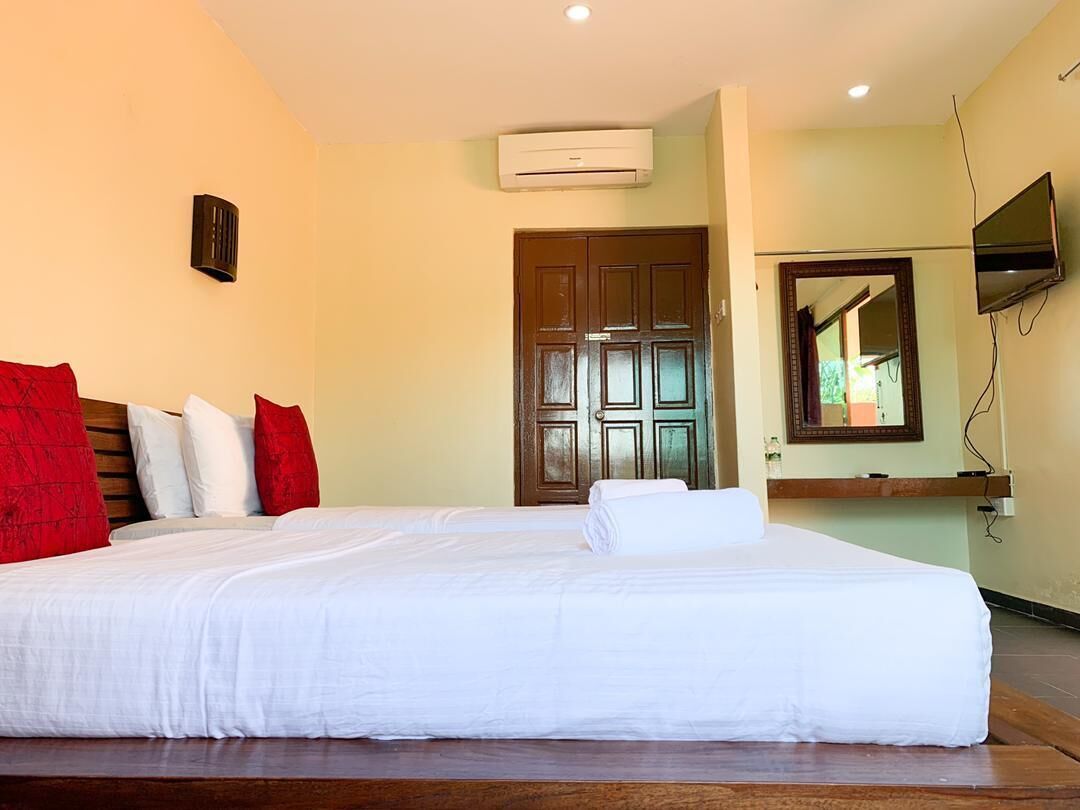 Habitación de hotel con una cama grande, cabecera de madera, televisor de pantalla plana en la pared y una puerta con espejo.