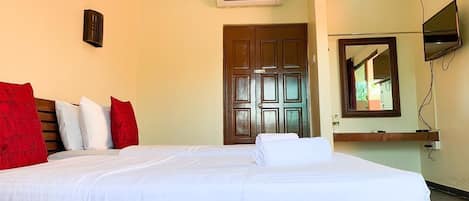 Habitación de hotel con una cama grande, cabecera de madera, televisor de pantalla plana en la pared y una puerta con espejo.