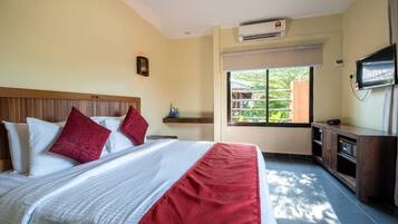 Quarto de hotel com cama, televisão, janela e ar condicionado.