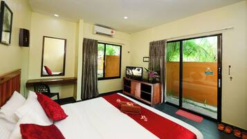 A hotel room with a bed, a desk, a television, and a sliding glass door to the outside.