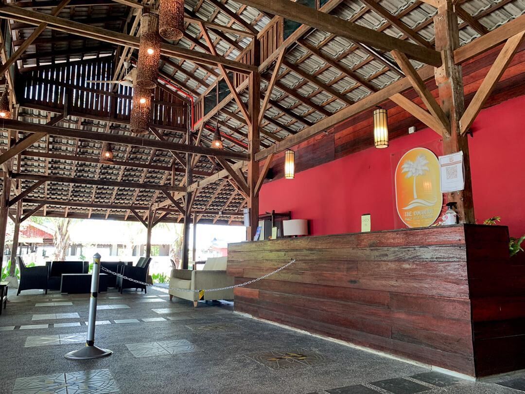 A reception area with a wooden reception desk, a red wall, and a ceiling with exposed beams and hanging lights.