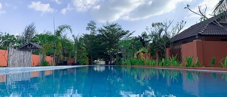 Piscina azul cristalina con reflejos de árboles y un cielo despejado.