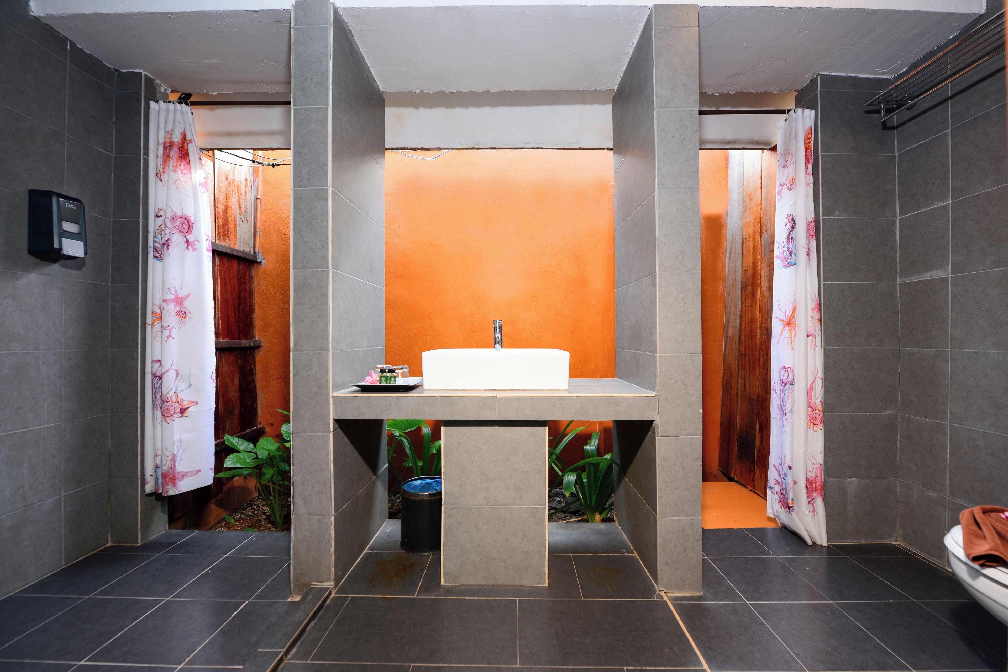 A bathroom with a central sink, tiled walls, and a shower area.