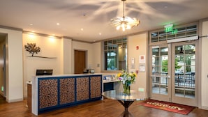 A reception area with a wooden floor, a reception desk, a vase with flowers, and an exit sign.