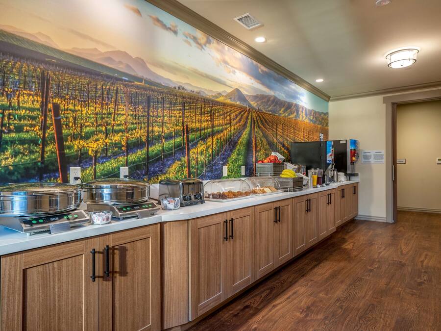 A kitchen with a long counter, equipped with a coffee maker, toaster, and food display.